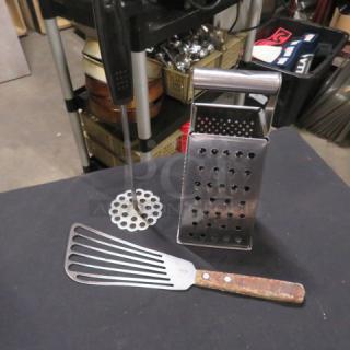 Assorted cooking utensils: metal slotted spatula, potato masher, and box grater. Used condition with visible wear.