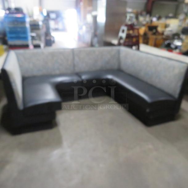 C-shaped booth with black cushioned seat and patterned cushioned back, in good condition, ideal for dining or lounge areas.