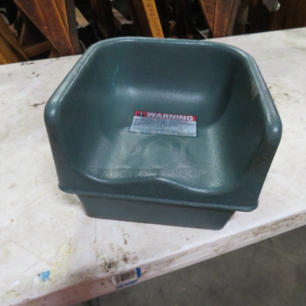Green Cambro booster seat, molded plastic, good condition, visible safety warning label on inner backrest.