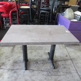 Gray table top on dual pedestal bases, 48x30x30 inches, excellent condition. Auction item in warehouse setting.