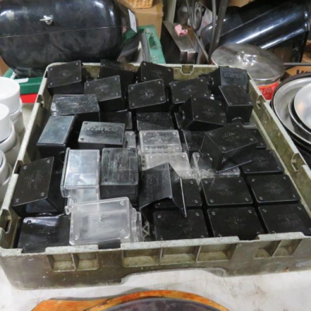 Dishwasher rack with assorted black and clear sugar pack holders in used condition, stackable design.