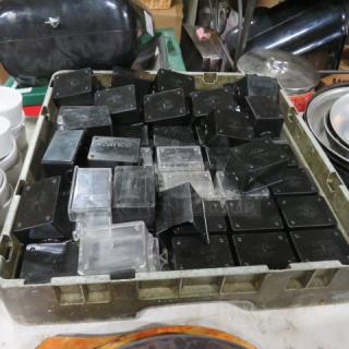 Dishwasher rack with assorted black and clear sugar pack holders in used condition, stackable design.