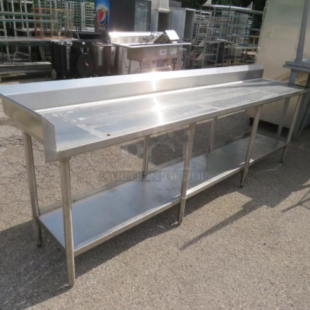 Stainless steel table with left splash/back splash, under shelf; dimensions 112x24x40 inches, good condition.