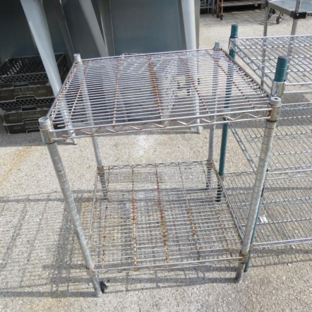 One green Metro shelf unit with two wire shelves, 24x24x32 inches. Minor rust, sturdy frame. Suitable for storage.