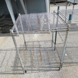 One green Metro shelf unit with two wire shelves, 24x24x32 inches. Minor rust, sturdy frame. Suitable for storage.