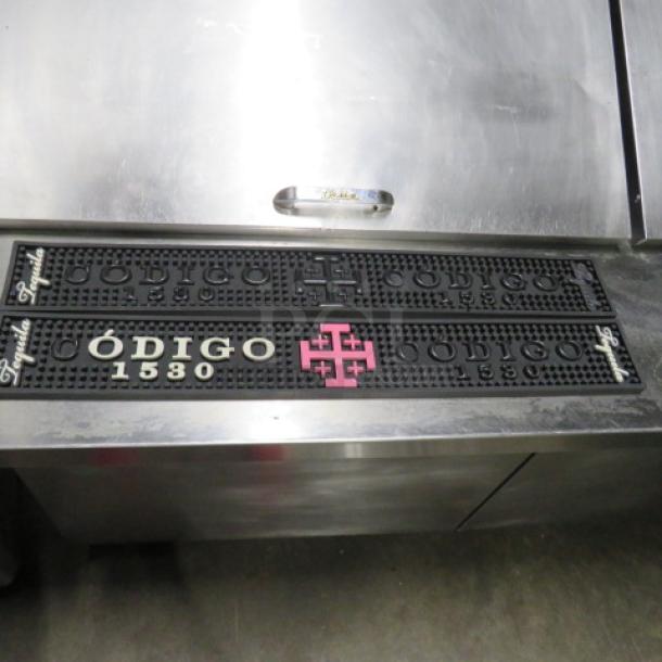 Black Codigo 1530 bar mat with raised lettering and pink logo, in good condition. Ideal for bartops.