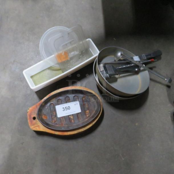 Lot of miscellaneous kitchen items including a metal pot, plastic containers, utensils, and a cast iron grill with number 350 tag.