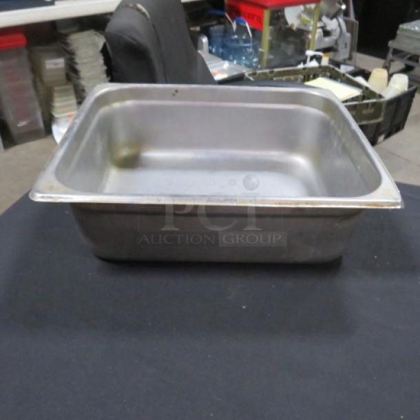Half-size, 4-inch deep hotel pan in used condition. Stainless steel with visible wear. Suitable for commercial kitchen use.