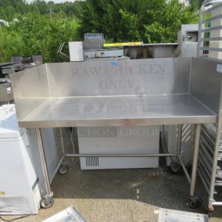 Stainless steel table with right/left backsplash, on casters, 60x30x51 inches, marked "RAW CHICKEN ONLY", good condition.