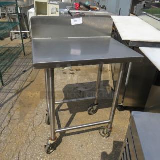 Stainless steel table with back splash on casters, dimensions 30"x22"x44". Slightly used, ideal for kitchen prep.