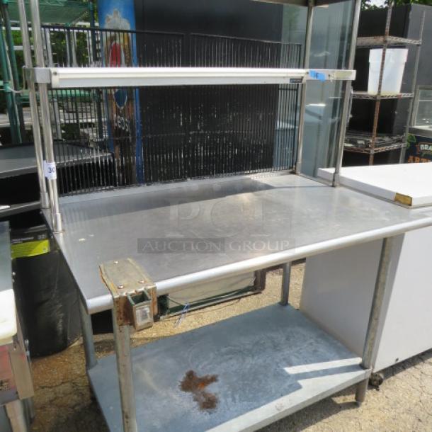 Stainless steel table with under shelf, two over shelves, 36" San Jamar ticket rail, can opener bracket, 48x31x66.5 inches.