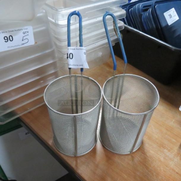 Two cylindrical metal pasta baskets with blue handles. Auction tags 90 and 40 visible. Good condition.