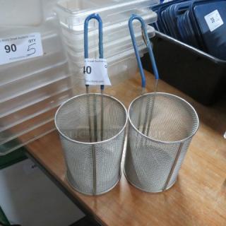 Two cylindrical metal pasta baskets with blue handles. Auction tags 90 and 40 visible. Good condition.