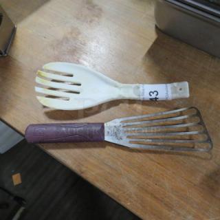 Two assorted utensils on a wooden surface: a white slotted spoon with a tag labeled "43" and a metal slotted spatula. Used condition.
