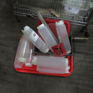 Lot of miscellaneous kitchen items, including clear plastic squeeze bottles and metal utensils in a red tray. Marked tags 48, 76 visible.