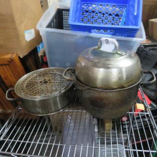 Metal cookware with lid and steamer, visibly worn. Includes storage bins in the background, with auction lot tag "50".