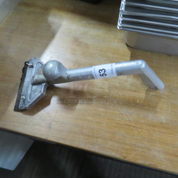 Griddle scraper with angled metal handle, used condition, marked with label number 53, on wooden surface.