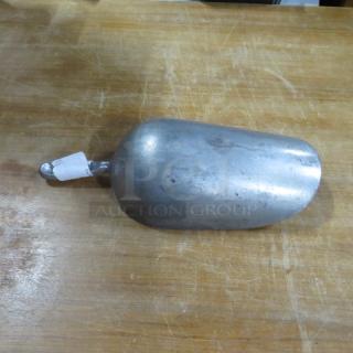 85oz aluminum scoop on wooden surface, showing wear consistent with use. Small white tag attached to handle.