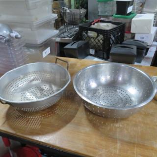 Assorted colanders, metal, two sizes. Each with perforated design and handles. Used condition, no visible branding.