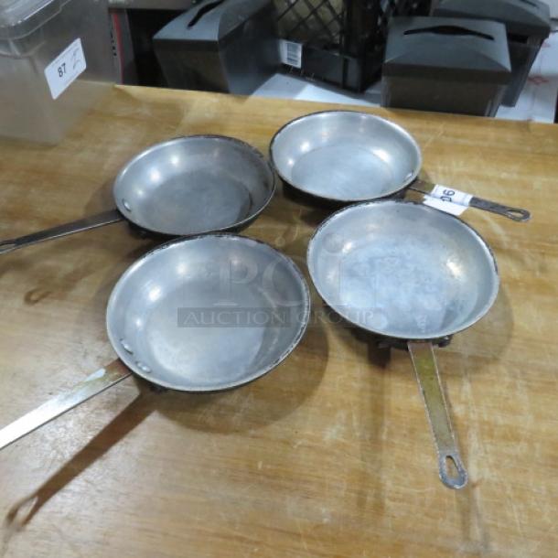 Set of four 9-inch sauté pans, used condition, metal construction with long handles. Item labeled "4XBID."