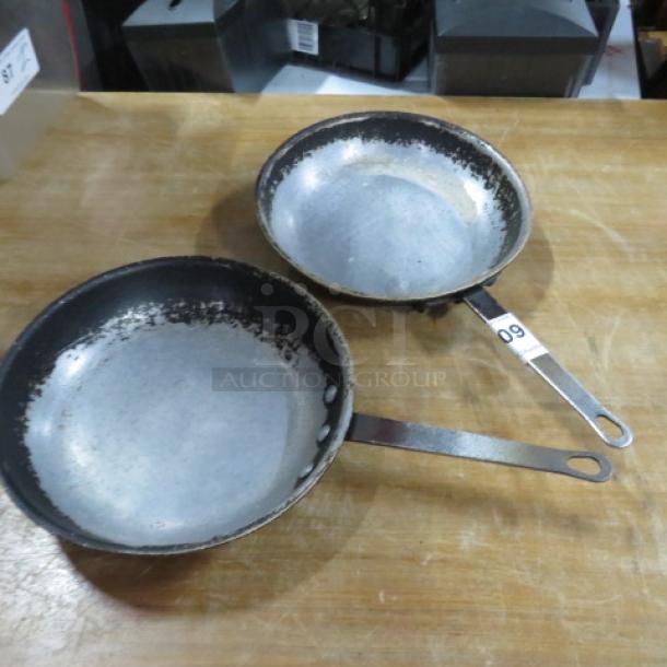 Two 11-inch sauté pans with metal handles, showing signs of wear. Handle marked with lot number 09.