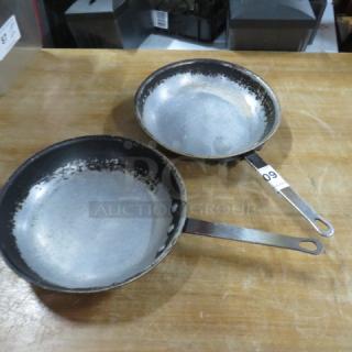 Two 11-inch sauté pans with metal handles, showing signs of wear. Handle marked with lot number 09.