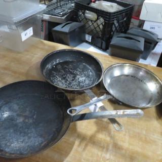 12.5-inch sauté pan, worn condition, metal construction, long handle. Additional kitchen pans visible, indicating similar use.