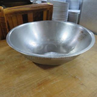 18.5-inch stainless steel mixing bowl, slightly worn, sits on a wooden surface; ideal for kitchen use.