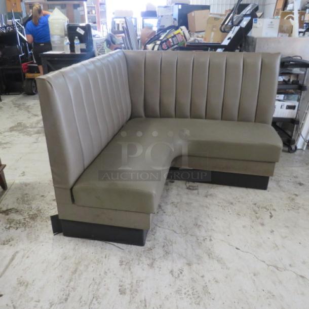 Gray cushioned corner booth, dimensions 58x27x42 inches, in a commercial setting. Vertical tufted backrest.