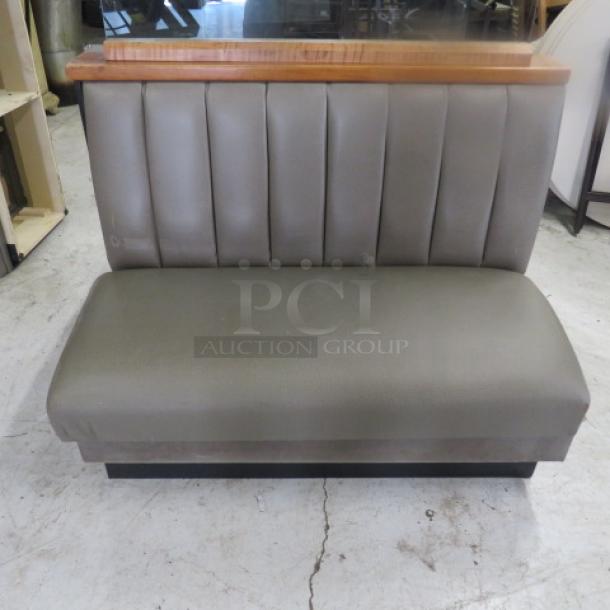 Double-sided booth with wooden top rail, glass divider, and grey cushioned seat and back, 50x50x52.