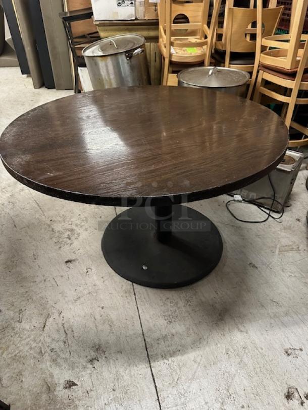 Round solid wood table on a black pedestal base, 48x30 inches. Dark wood finish, good condition, ideal for dining spaces.