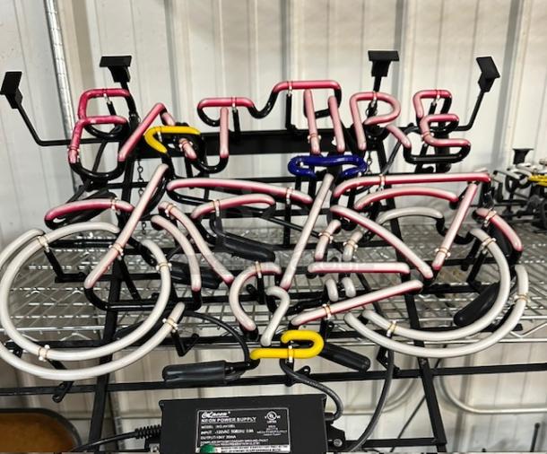 Neon sign featuring "FAT TIRE" text and bicycle design. Multicolored tubing on black frame, in good condition.