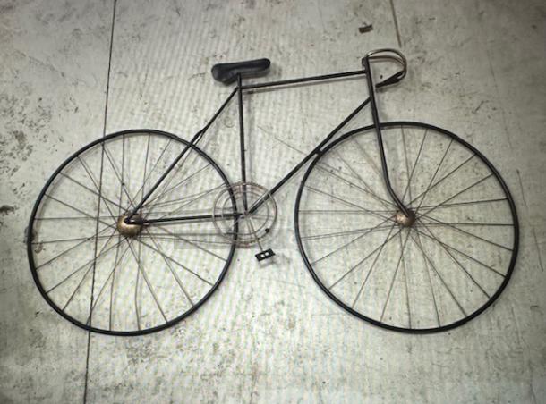 Metal wall decor shaped like a vintage bicycle, featuring intricate spokes and handlebars. In good condition.