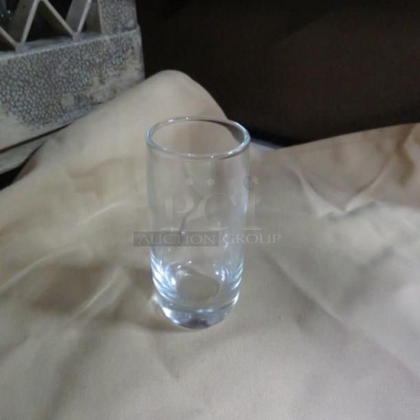 Clear 2oz shot glass, new condition, plain design. No visible markings or labels.