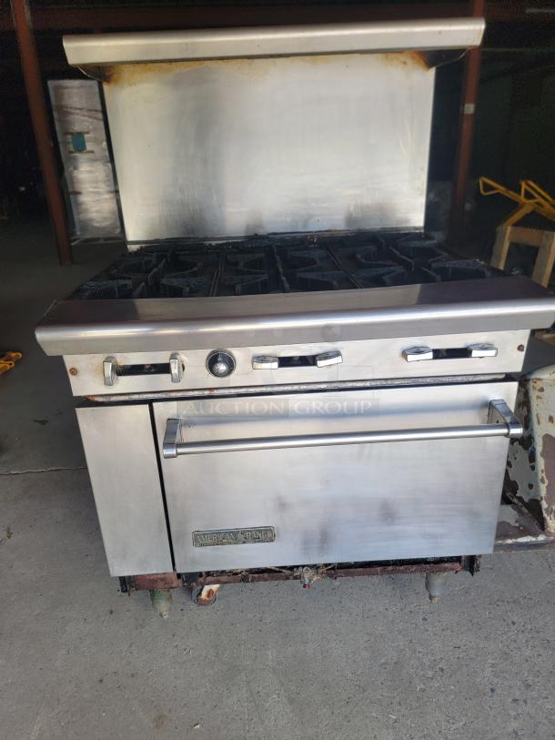 Commercial American Range stove with 6 burners and oven, stainless steel, used condition, visible rust on lower section.