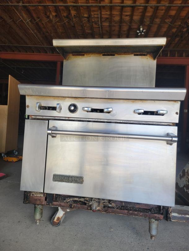 Commercial stainless steel range by American Range, visible rust, missing parts, label reads "American Range." Used condition.