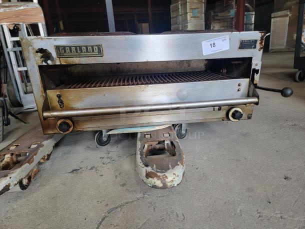 Garland commercial broiler in used condition, stainless steel body with markings, control knobs, and visible wear.