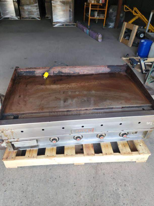 Vulcan commercial griddle on pallet, used condition, stainless steel, four control knobs, visible wear and rust on cooking surface.