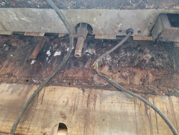 Rusty metal surface with exposed wires, showing signs of wear and corrosion. Potential restoration project.