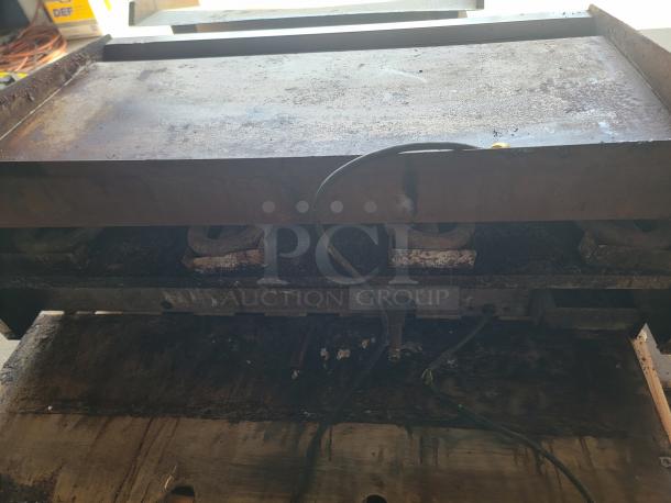 Large industrial grill, visibly used with multiple burners, metal surface showing signs of rust and wear. Suitable for refurbishment.