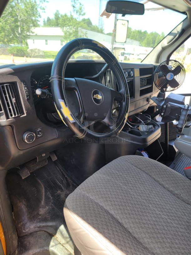 Chevrolet vehicle interior with logo on steering wheel cover, dashboard fan, and cloth seat. Clean condition, functional layout.