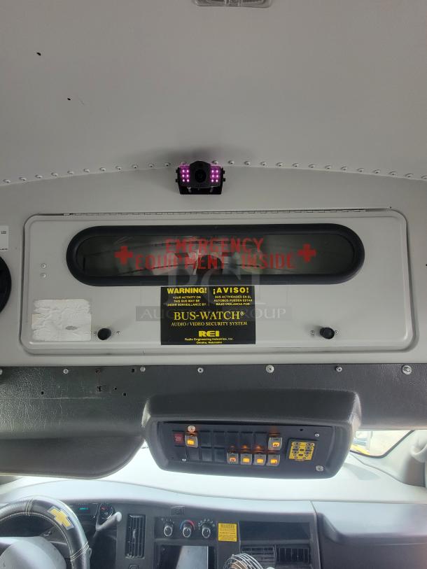 Bus interior security system with camera and control panel. "Emergency Equipment Inside" and "Bus-Watch" labels visible.