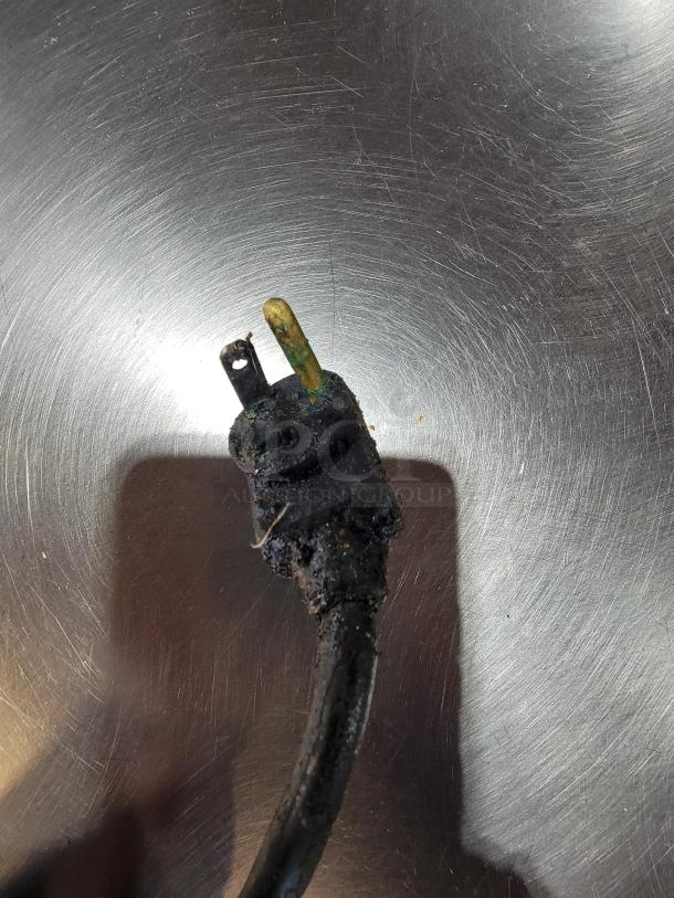 A damaged and corroded power plug on a metallic surface; part of a True TRCB-110 Chef Base.