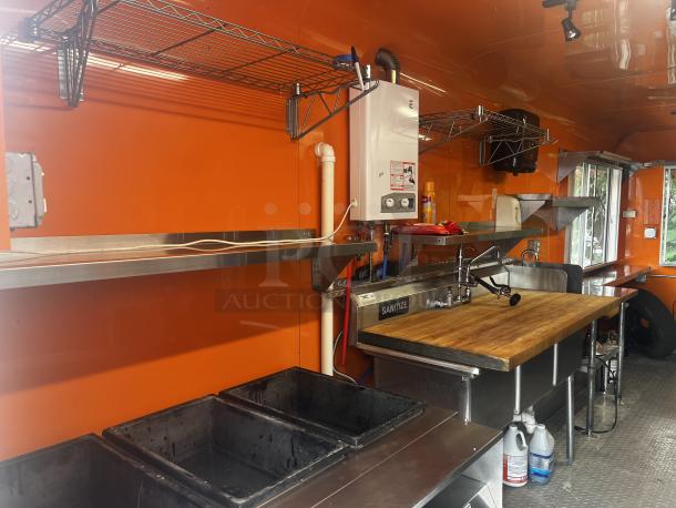 2014 Quality Trailers mobile kitchen interior with stainless steel sink, cutting board, and shelves. Includes water heater and sanitation setup.