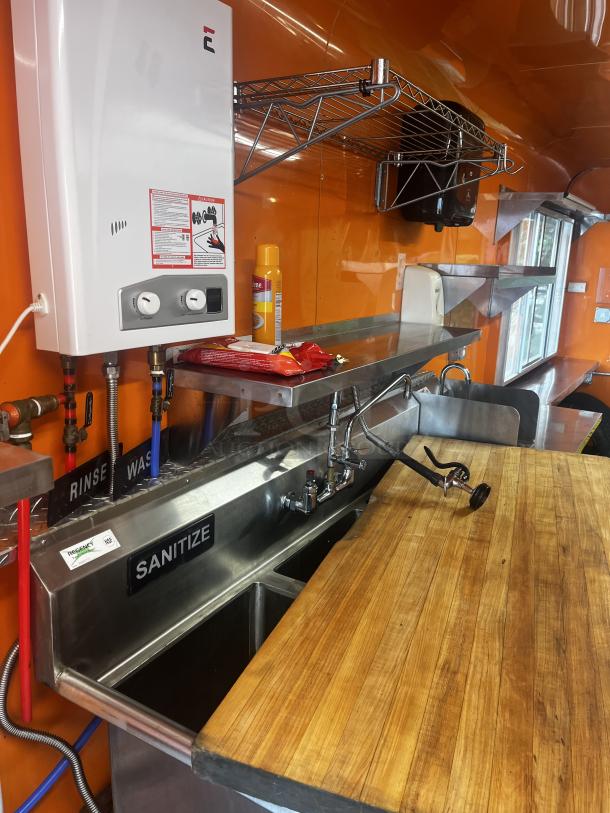 2014 Quality Trailers mobile kitchen interior with 3-compartment sink, wood counter, wall shelf, and Protex II heater.