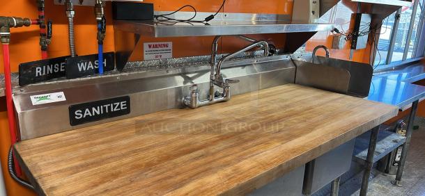 2014 Quality Trailers mobile kitchen sink area with wash, rinse, sanitize signs. Features stainless steel fixtures.