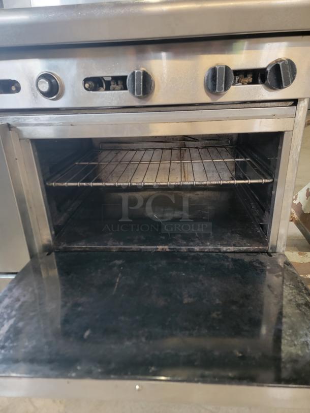 American Range commercial gas range with 6 burners and oven. Features four control knobs and a spacious interior. Used condition.