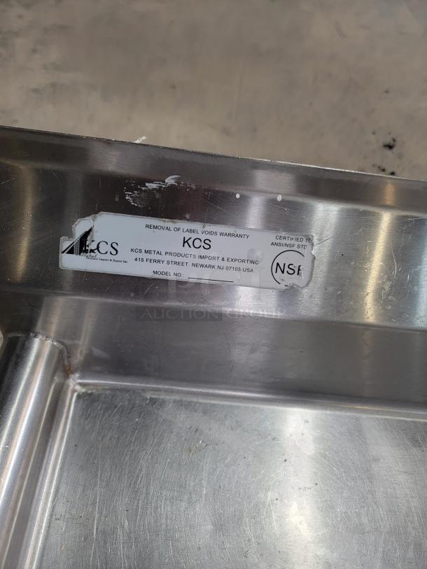 4' stainless dishwashing table, left-side configuration, by KCS. Shows wear. Label: removal voids warranty, certified ANSI/NSF.