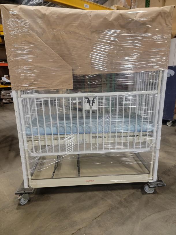 Hospital-grade infant crib, Hard General Pediatric model, sturdy steel frame, confetti epoxy finish, wrapped for protection.