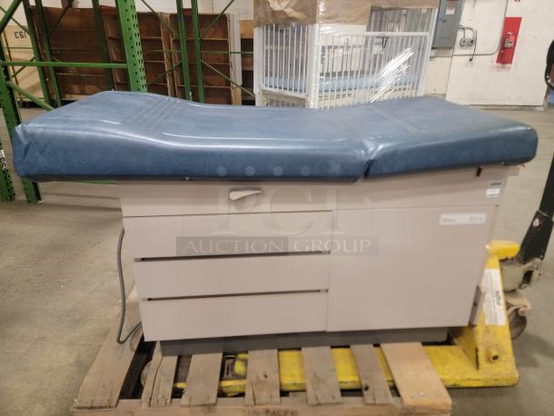Ritter 104 examination table with blue cushioned top, three storage drawers, sturdy design, suitable for various uses.